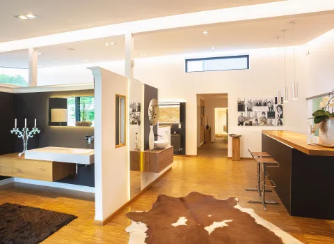 Ein offener Showroom präsentiert eine elegante Badausstellung mit Designerwaschbecken, Holzmöbeln und moderner Beleuchtung.