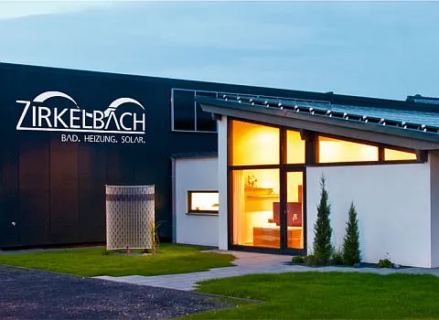 Ein Firmengebäude mit dem Schriftzug Zirkelbach – Bad, Heizung, Solar auf einer schwarzen Fassade.