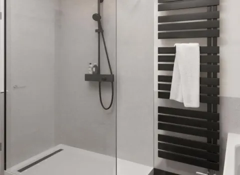 Dusche mit Glasabtrennung und Duschwanne. Armaturen, Badheizkörper und Bodenfliesen sind schwarz.