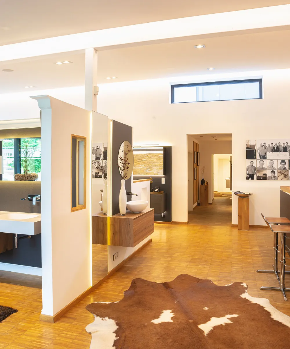 Ein offener Showroom präsentiert eine elegante Badausstellung mit Designerwaschbecken, Holzmöbeln und moderner Beleuchtung.