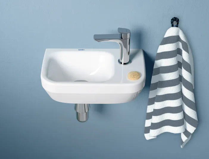 Wandhängender Gästebad-Waschtisch von Duravit vor einer blauen Wand.